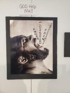 Photograph at speak your peace event titled "God Help Me!". Shows a man screaming in the air with the words: anger, frustration, pain, hopelessness