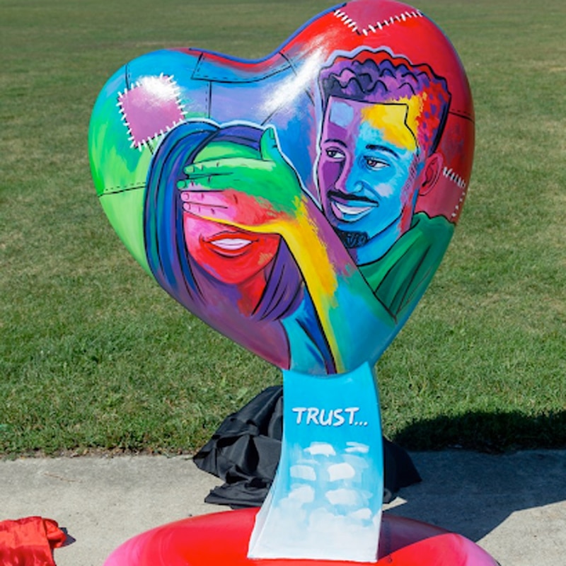 a heart painted with the image of a man and woman smiling created for parade of hearts