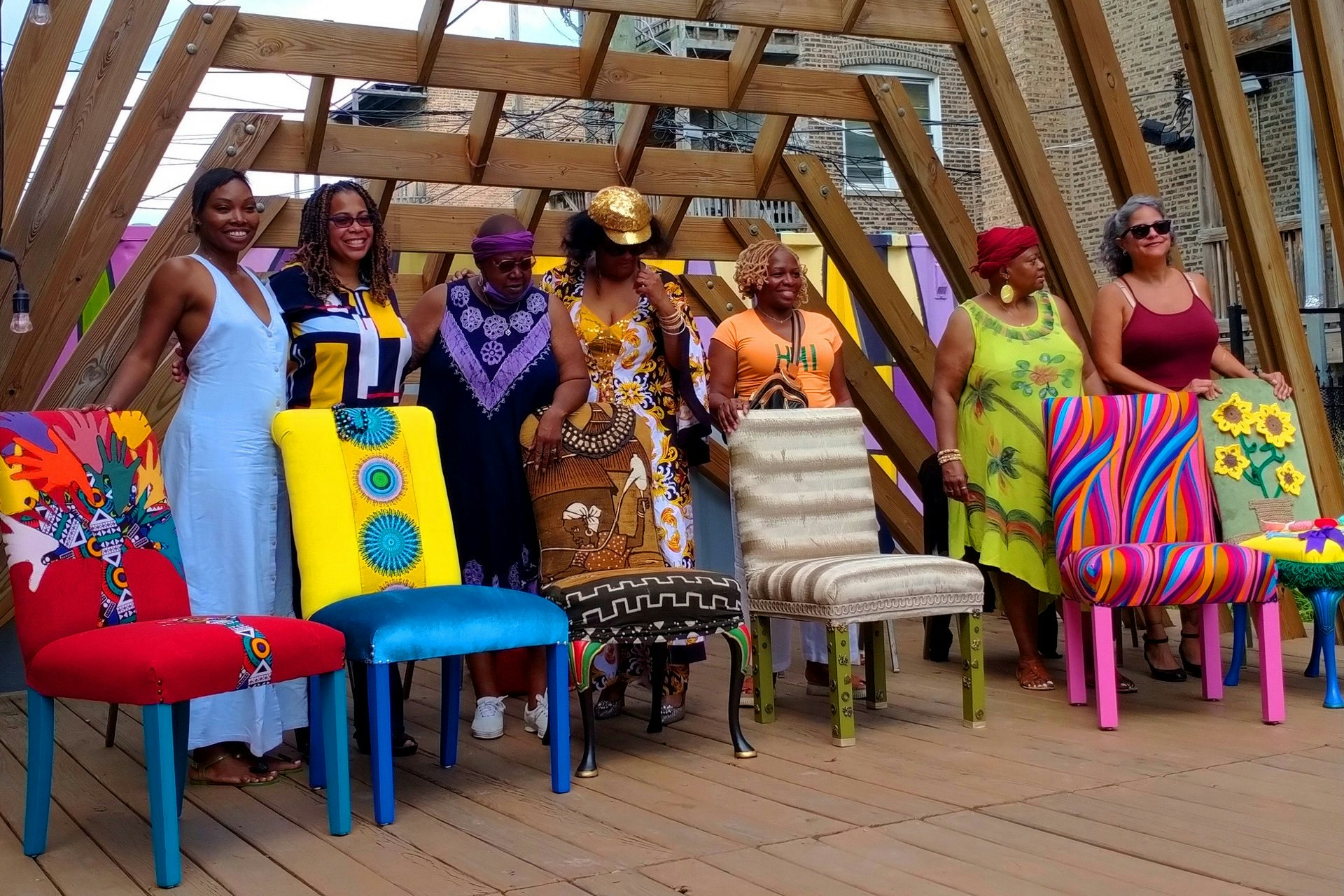 artists posing with the chairs they created