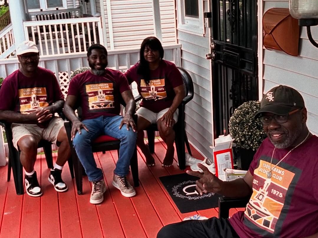 A group of people in block club t-shirts on someone's porch at the block club party