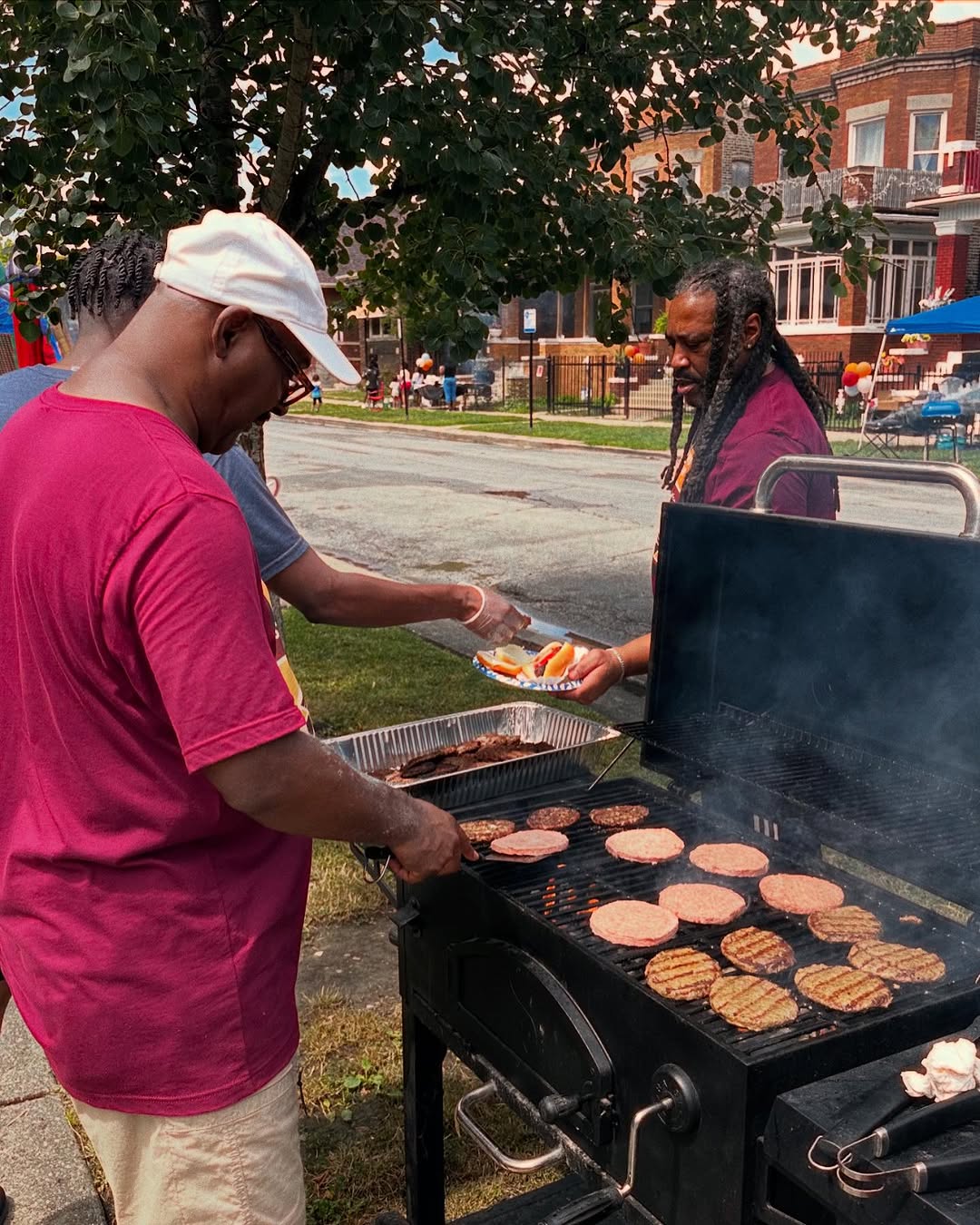 A block club member grilling at the block party and someone being served a burger