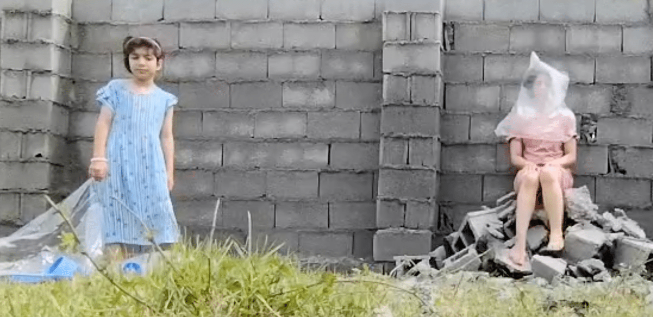 photograph of two children in front of a brick wall